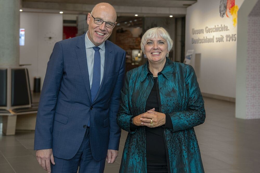 Harald Biermann und Claudia Roth stehen nebeneinander im Haus der Geschichte.