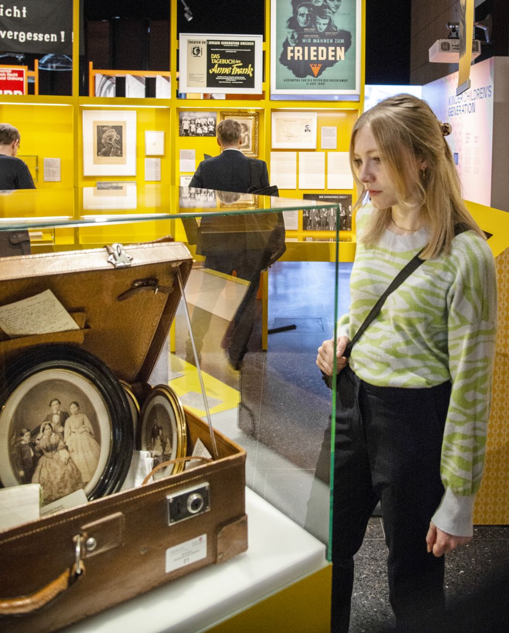 A visitor looks at a suitcase in a display case. Inside are the belongings of a Jewish family who was murdered in the Holocaust.