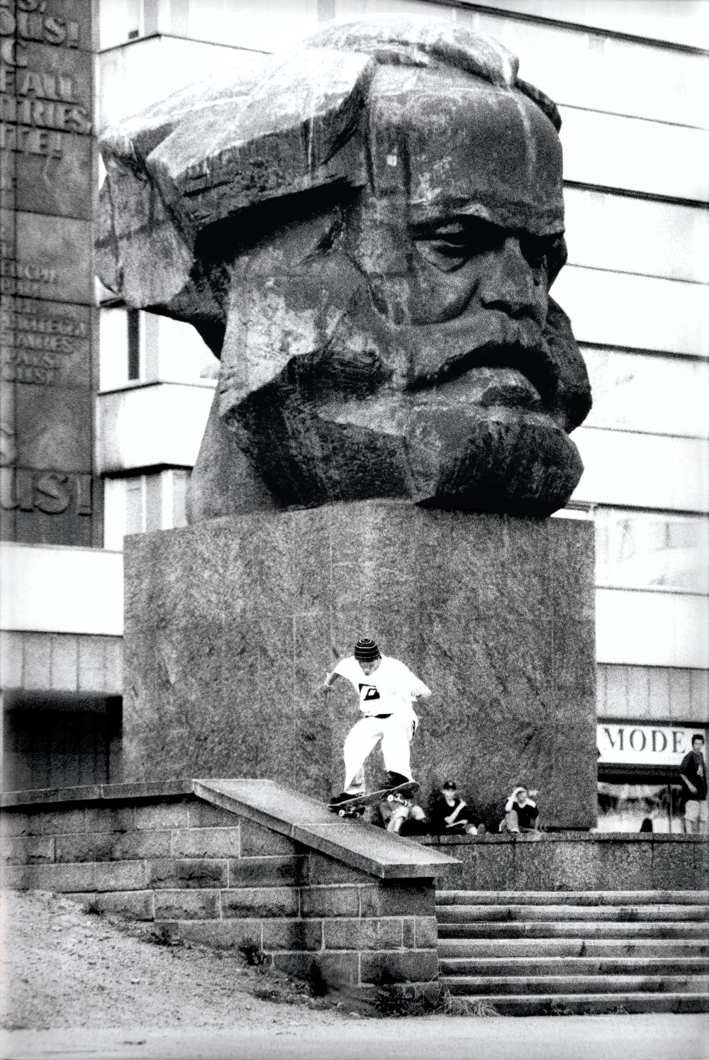 Ein Skater macht einen Trick vor einer großen Porträtbüste von Karl Marx.