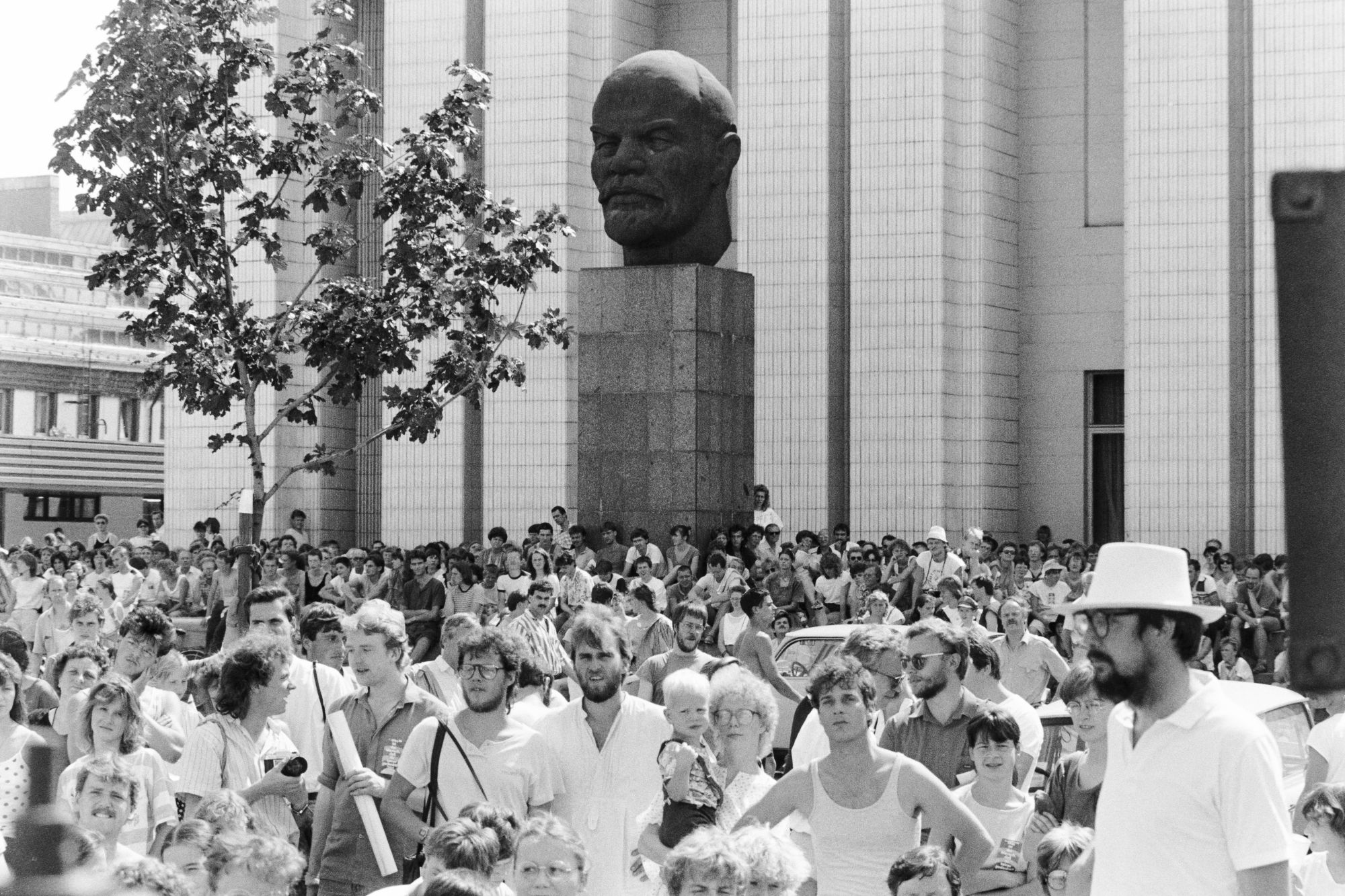 Viele Menschen in weißer Kleidung demonstrieren gemeinsam. Im Hintergrund ist eine Leninbüste zu sehen.